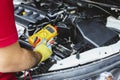 A mechanic holds a digital multimeter to check the car electrical system Royalty Free Stock Photo