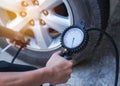 Mechanic inflating tire and checking air pressure with gauge