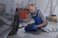 Mechanic inflating a tire and checking air pressure with a gauge