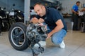 mechanic inspecting engine with rear wheel attached