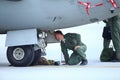 A mechanic is inspecting parts of an Alenia C-27J Spartan military cargo plane after landing on an airbase Royalty Free Stock Photo