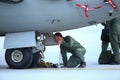 A mechanic is inspecting parts of an Alenia C-27J Spartan military cargo plane after landing on an airbase Royalty Free Stock Photo