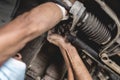 A mechanic inspects the engine support underneath a car, tightening it with a telescoping wrench