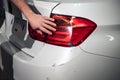 A mechanic inspects the headlight of a white car