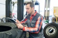 mechanic leaning on tyre to write on clipboard Royalty Free Stock Photo
