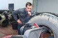 Mechanic looking pensively at large tyre Royalty Free Stock Photo