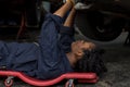 Mechanic lying down and working under car at auto service garage. Technician vehicle maintenance and checking under car at automot Royalty Free Stock Photo