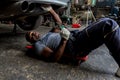 Mechanic lying down and working under car at auto service garage. Technician vehicle maintenance and checking under car at automot Royalty Free Stock Photo