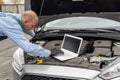 Mechanic making diagnostic of a car with laptop