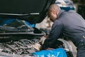 Mechanic male car engine service underhood checking oil replace in broken part at auto garage