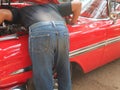 Mechanic man checking engine of red antique classic car Royalty Free Stock Photo