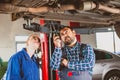 Mechanic man examining car with trainee girl