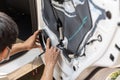 Mechanic man installing speaker on vehicle door part in garage Royalty Free Stock Photo