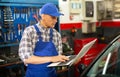 Mechanic man with laptop making car diagnostics at service Royalty Free Stock Photo
