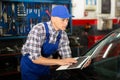 Mechanic man with laptop making car diagnostics at service Royalty Free Stock Photo