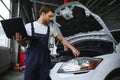 Mechanic man mechanic manager worker using a laptop computer checking car in workshop at auto car repair service center Royalty Free Stock Photo