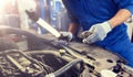 Mechanic man with pliers repairing car at workshop