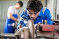 Mechanic man repairing brake disc of car using lathe tool polishing at garage. Engineer using flashlight and inspector the surface