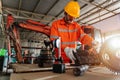 A mechanic man Small Excavator Repair and Maintenance. asian Heavy Equipment Mechanic Trying to Find an Issue. Industrial Theme Royalty Free Stock Photo