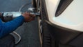 Mechanic man using electric drill to loosen the bolts of vehicle wheel for changing a car tire Royalty Free Stock Photo