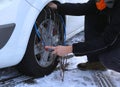 Mechanic mounting snow chains in the car tyre in winter on snow