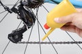 Mechanic oiling bicycle chain and gear with oil