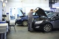 Mechanic in overalls opened hood of black car