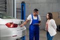 Mechanic with clipboard discusses car repair with woman Royalty Free Stock Photo