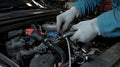 Mechanic performing maintenance on a car engine in a workshop during daytime Royalty Free Stock Photo