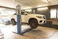 A mechanic performs routine maintenance on a luxury car lifted on a workshop hoist in a garage Royalty Free Stock Photo