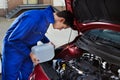 Mechanic pouring antifreeze into windscreen water tank