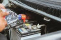 mechanic pouring distilled water to fill car battery in automobile repair service Royalty Free Stock Photo