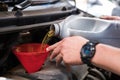 mechanic pouring oil to vehicle engine. serviceman changing motor oil in automobile repair service. maintenance & checkup in car