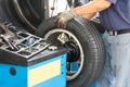 Mechanic attaching suitable weight onto wheel during wheel balancing at workshop