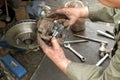 Mechanic pushing new brake pad into old caliper. Royalty Free Stock Photo