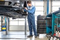 Mechanic Repairing Car On Hydraulic Lift