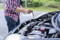 Mechanic repairing car with open hood,Side view of mechanic checking level motor oil