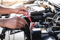 Mechanic repairman checking engine automotive in auto repair service and using digital multimeter testing battery to measure Royalty Free Stock Photo