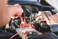 Mechanic repairman checking engine automotive in auto repair service and using digital multimeter testing battery to measure Royalty Free Stock Photo