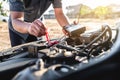 Mechanic repairman checking engine automotive in auto repair service and using digital multimeter testing battery to measure Royalty Free Stock Photo