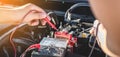 Mechanic repairman checking engine automotive in auto repair service and using digital multimeter testing battery to measure Royalty Free Stock Photo