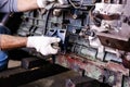 Mechanic repairs old motor of truck in a car repair station. Disassemble engine block vehicle. Motor capital repair. Car service Royalty Free Stock Photo