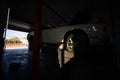 Mechanic in service repair station working with muscle car in lift at sunset shadows