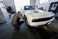 Mechanic in service repair station working with muscle car. Man worker diagnose the chassis