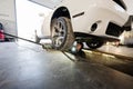 Mechanic in service repair station working with muscle car. Man worker inspects with lighter the running part of the wheel Royalty Free Stock Photo