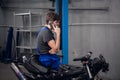 Mechanic sitting on a bike and talking on the phone