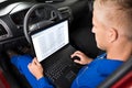 Mechanic Sitting In Car And Using Laptop