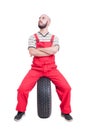 Mechanic sitting on car wheel isolated on white Royalty Free Stock Photo