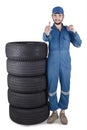 Mechanic with a stack of tires shows OK sign Royalty Free Stock Photo