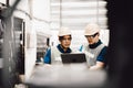 Mechanic and staff engineer talking nearby a machine in a big factory